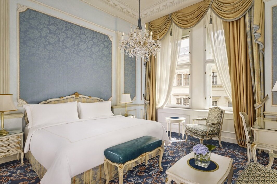 An elegant classic-style hotel bedroom with ornate decor and a seating area.