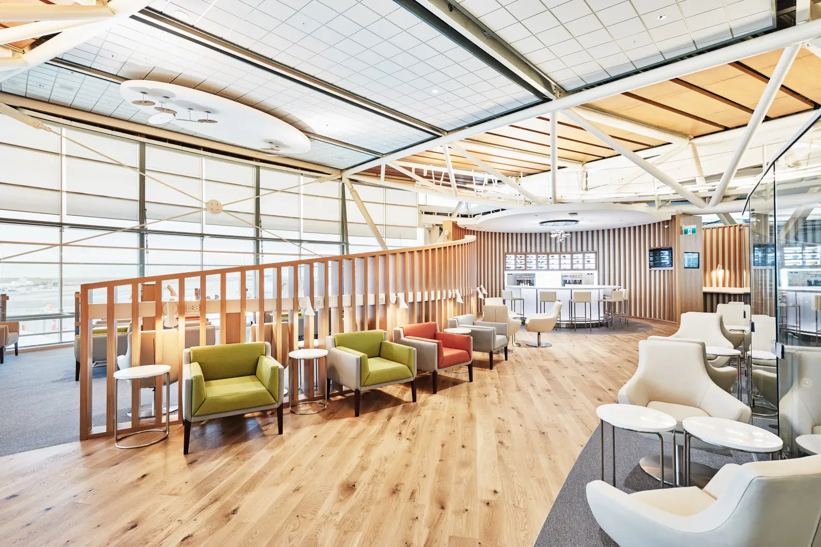 SkyTeam alliance lounge at Vancouver, floor-to-ceiling windows over the apron with wood slat dividers and coloured armchairs.