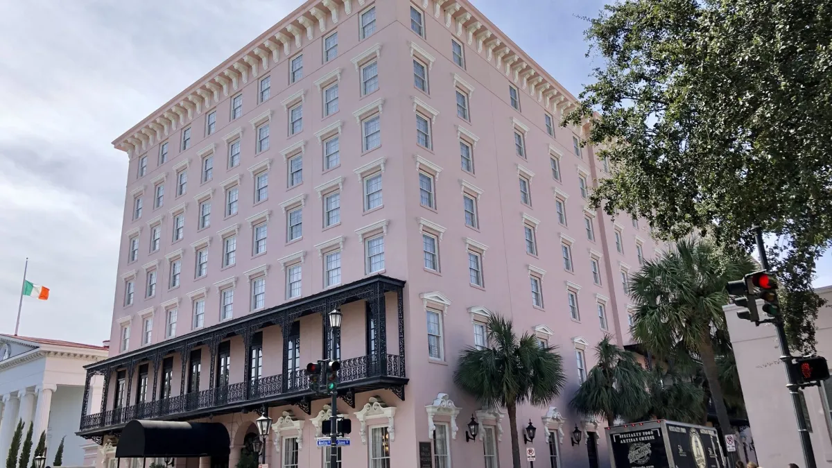 The pale stucco facade and wrought-iron balcony of a historic Wyndham Grand hotel in the Charleston French Quarter